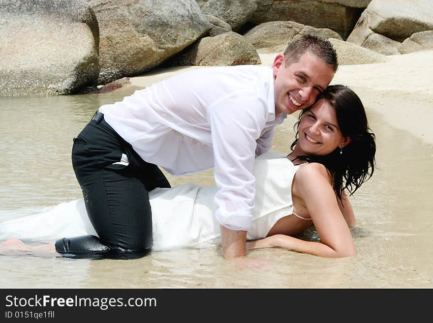 Bride and groom playing in the ocean.