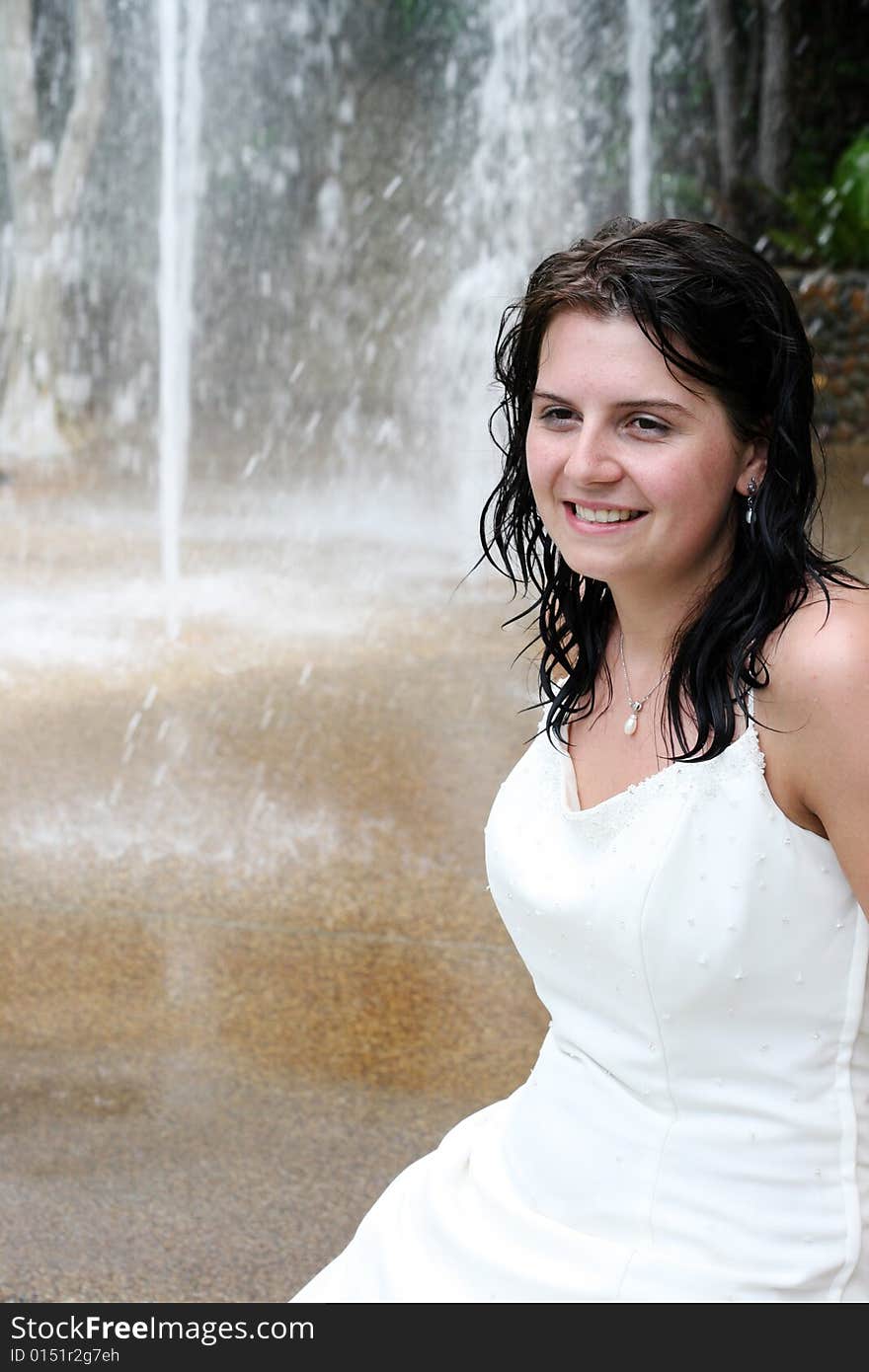 Beautiful young bride next to a waterfall on her wedding day.