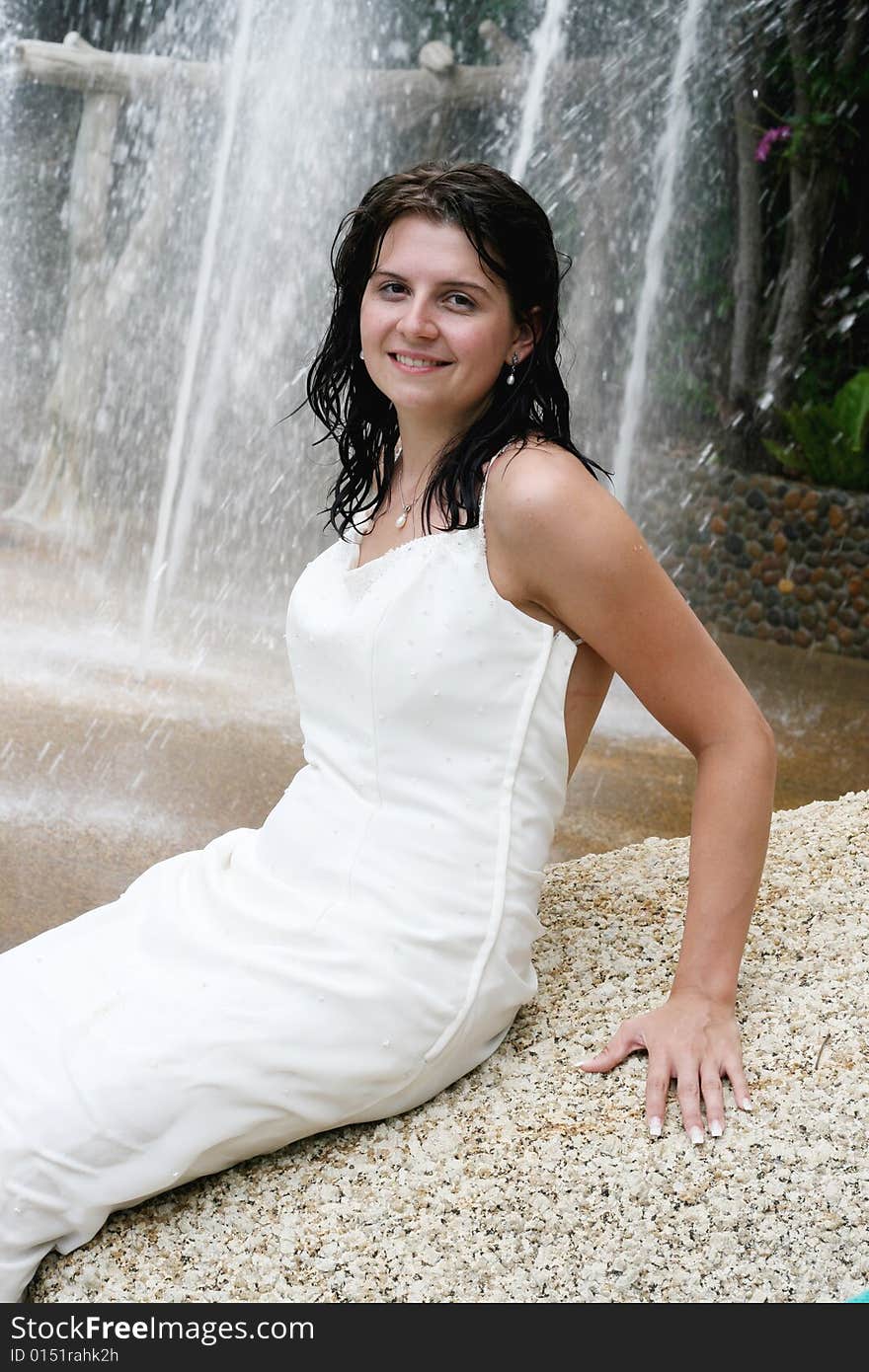 Beautiful young bride next to a waterfall on her wedding day.