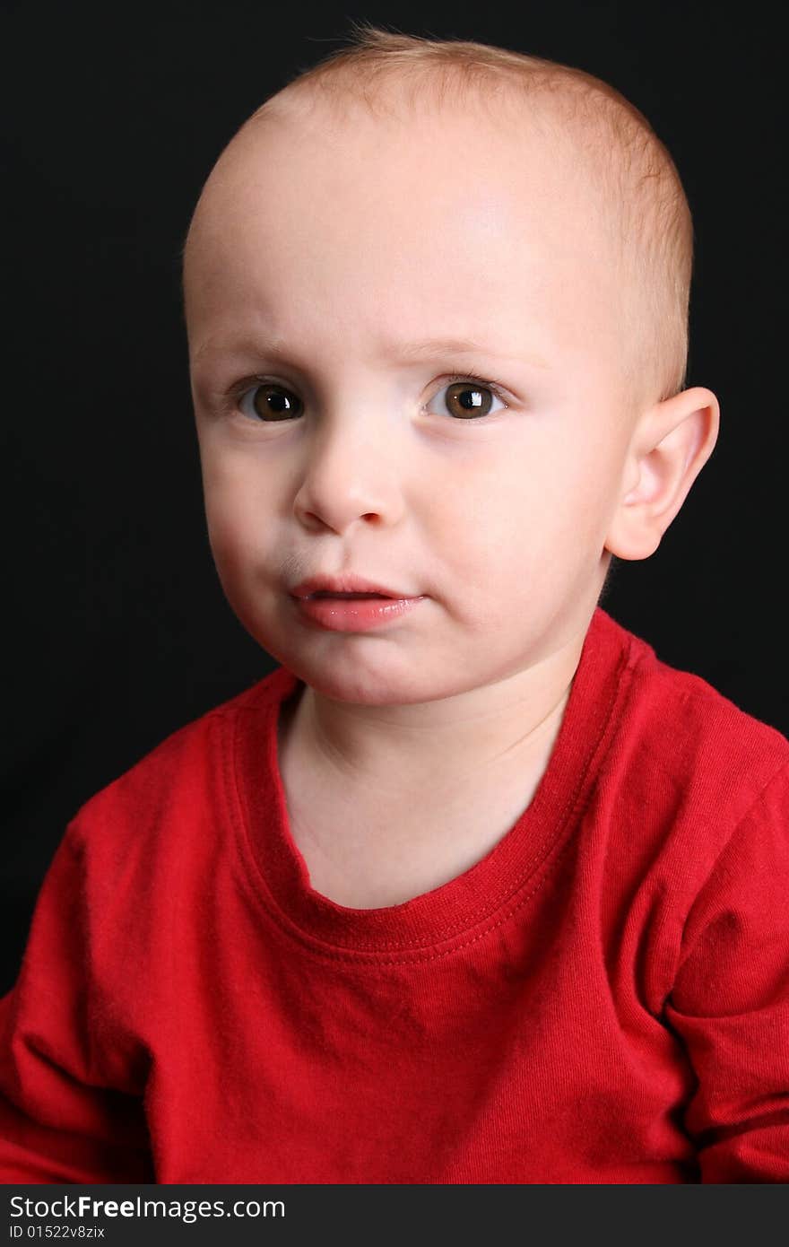 Blonde toddler against a black background with a serious expression