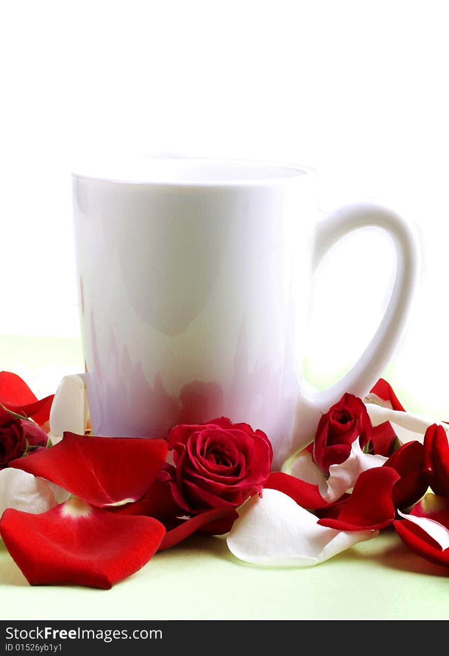 White cup and rose petals and heads