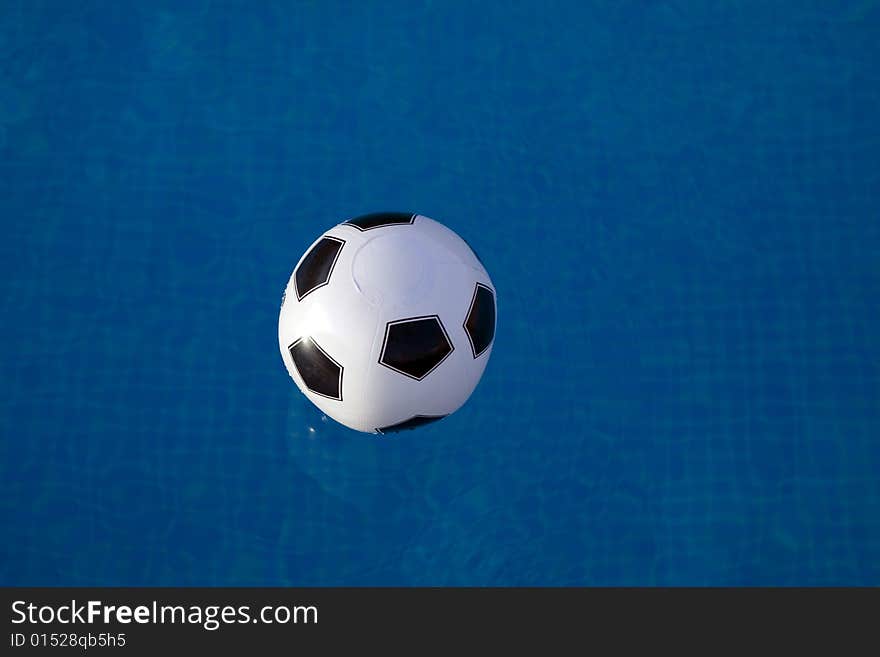 Inflatable plastic ball floating on a calm swimming pool