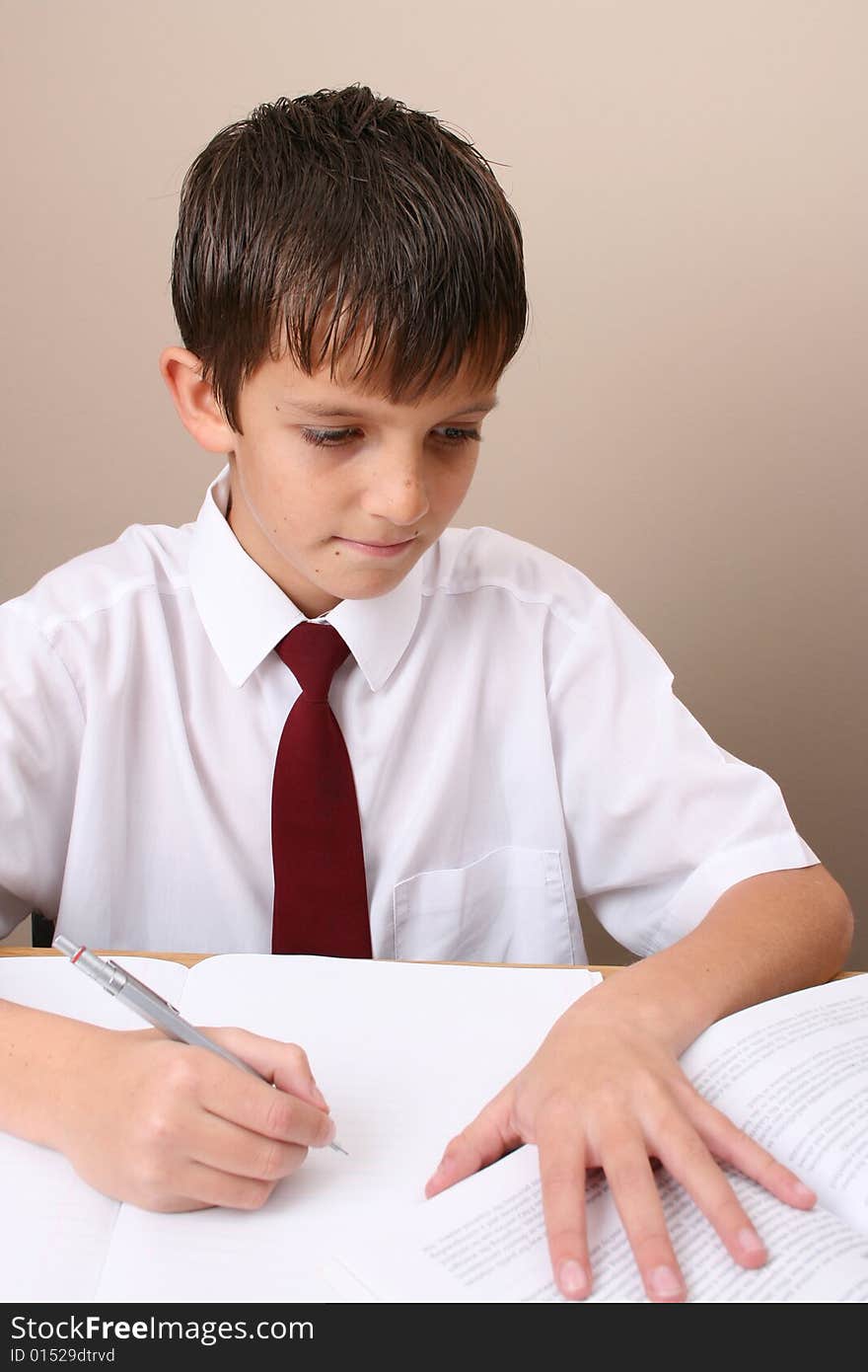 Teenage School boy busy with his homework, wearing uniform