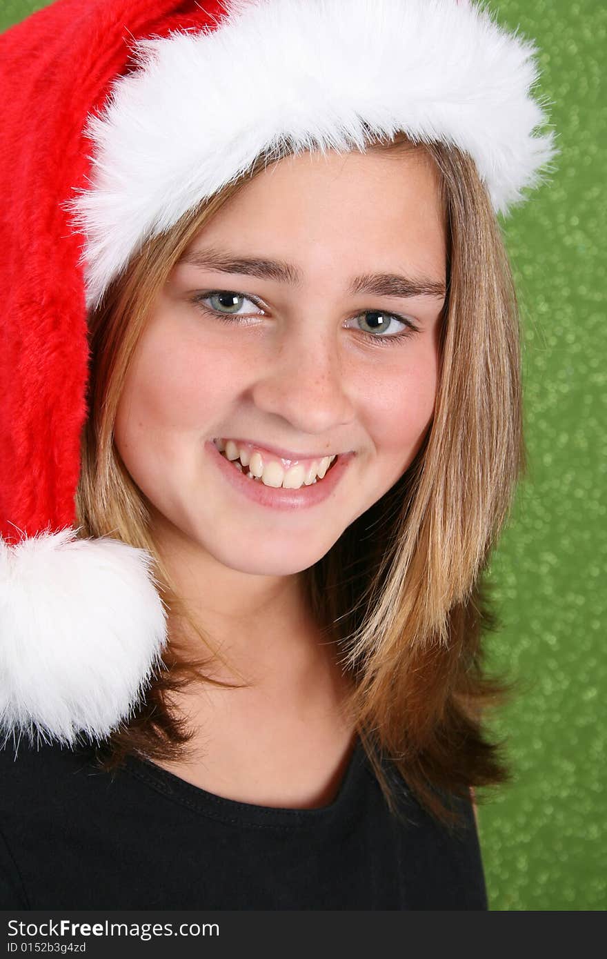 Smiling Teen wearing a christmas hat against a green background. Smiling Teen wearing a christmas hat against a green background