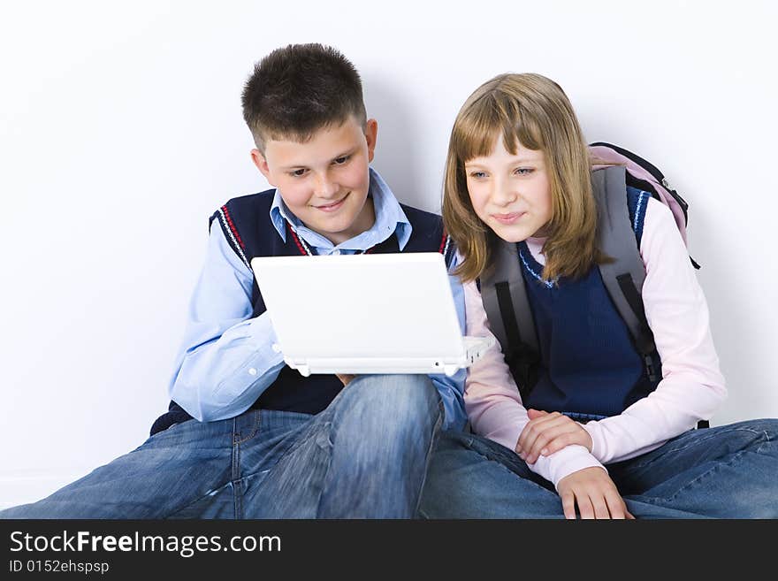 Boy and girl sitting on the floor. Boy showing something to girl on laptop. Front view. Boy and girl sitting on the floor. Boy showing something to girl on laptop. Front view.