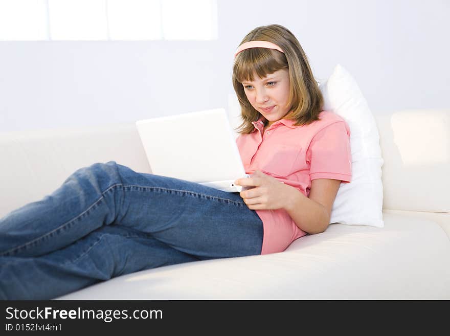 Young girl with laptop sitting on couch. She's smiling. Young girl with laptop sitting on couch. She's smiling.