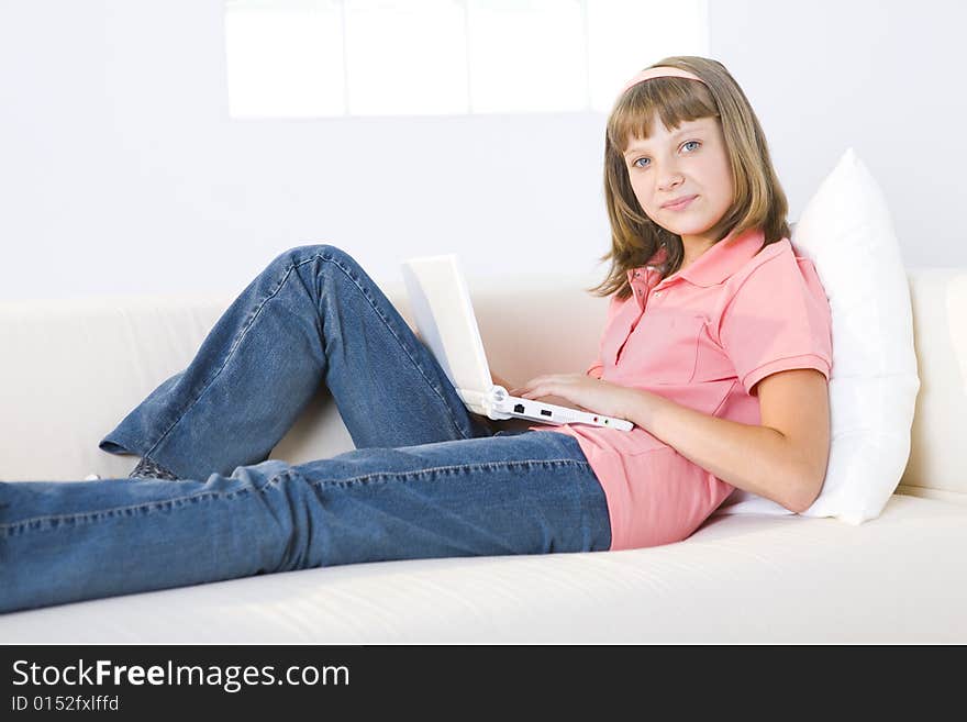 Young girl with laptop sitting on couch. She's smiling and looking at camera. Young girl with laptop sitting on couch. She's smiling and looking at camera.