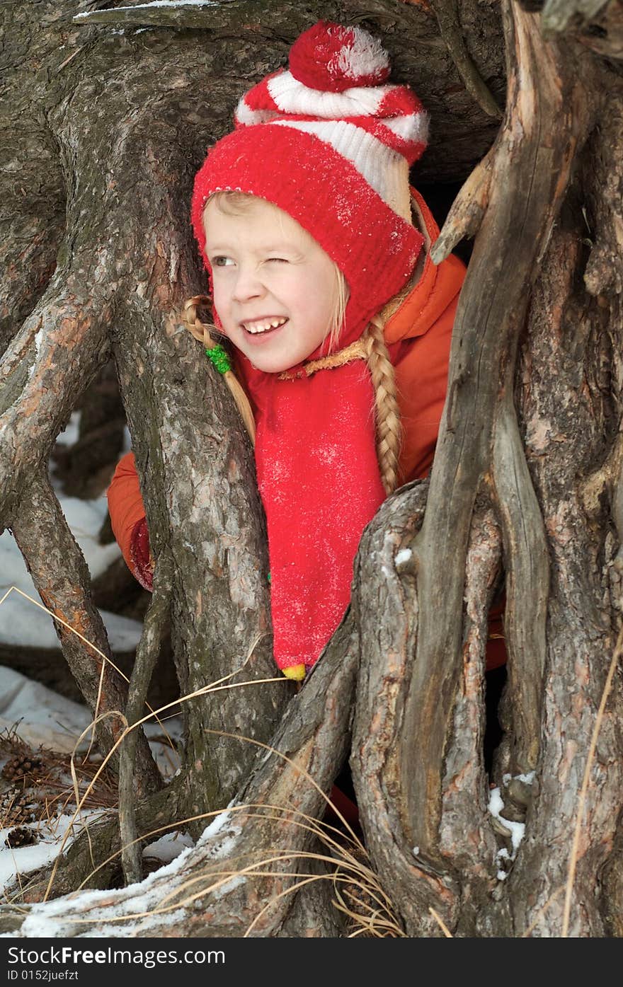 The girl costs between roots of a tree and has blinked one eye. The girl costs between roots of a tree and has blinked one eye