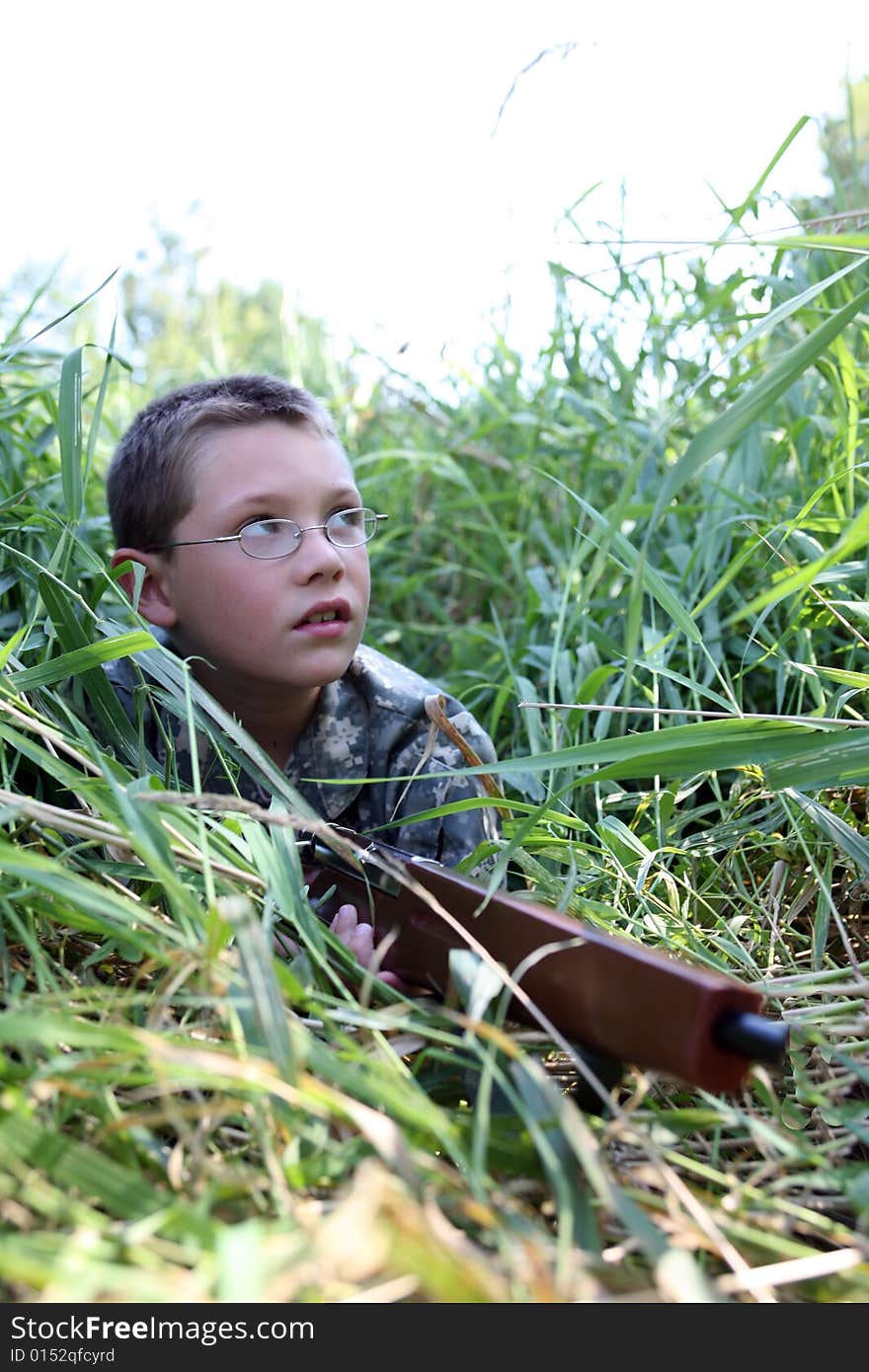 Child in grass with toy rifle looking up into the sky as if hunting birds. Child in grass with toy rifle looking up into the sky as if hunting birds