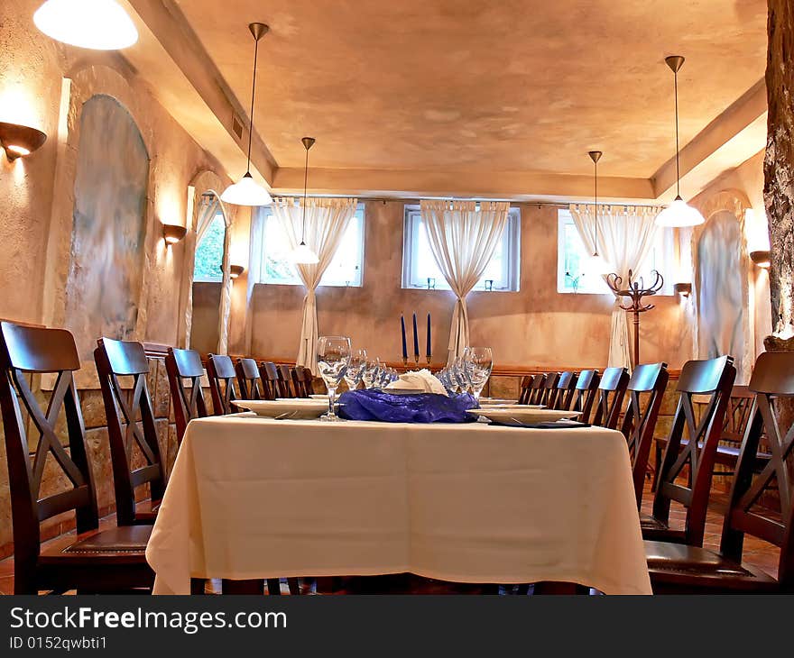 The beautiful romantic dining room with wooden chairs, long table, candlestick and blue decoration in atmospheric light.