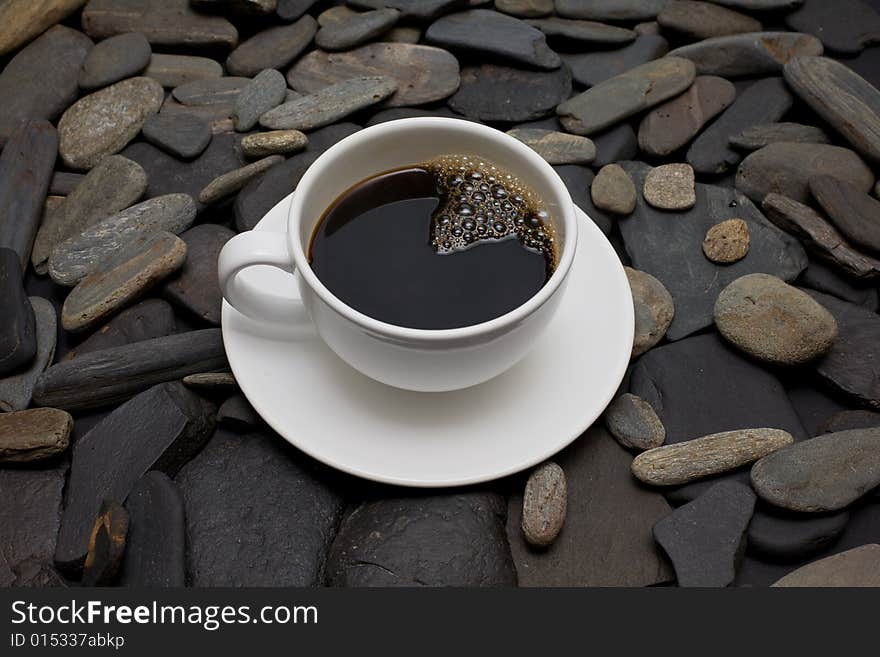 White cup of coffee against black stones