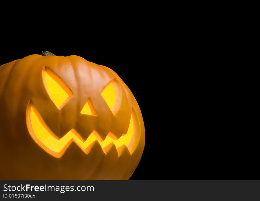 Scary Jack O' Lantern Lit Up on Black Background. Scary Jack O' Lantern Lit Up on Black Background