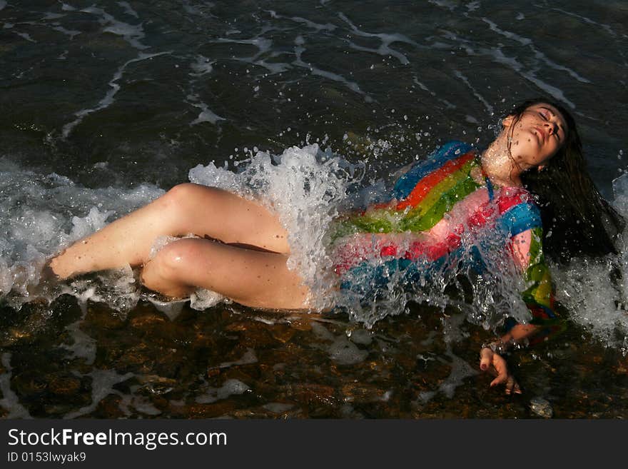 A brunette young beautiful woman wet by the sea water