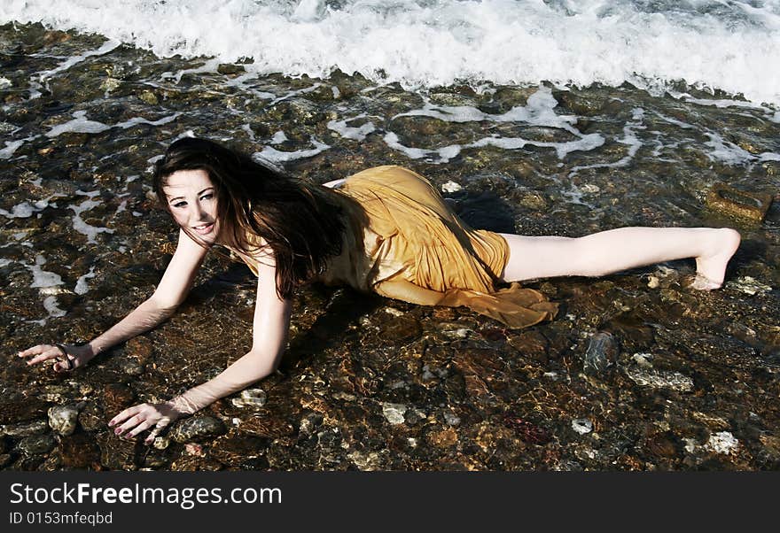 A brunette young beautiful woman wet by the sea water