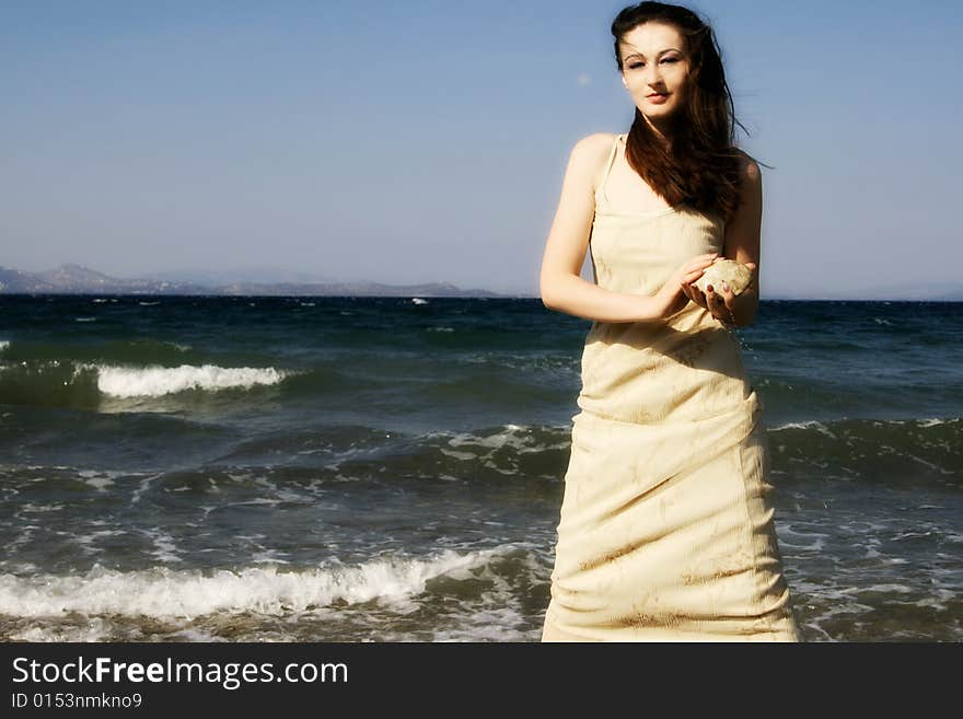 A young brunette beautiful woman by the windy seaside