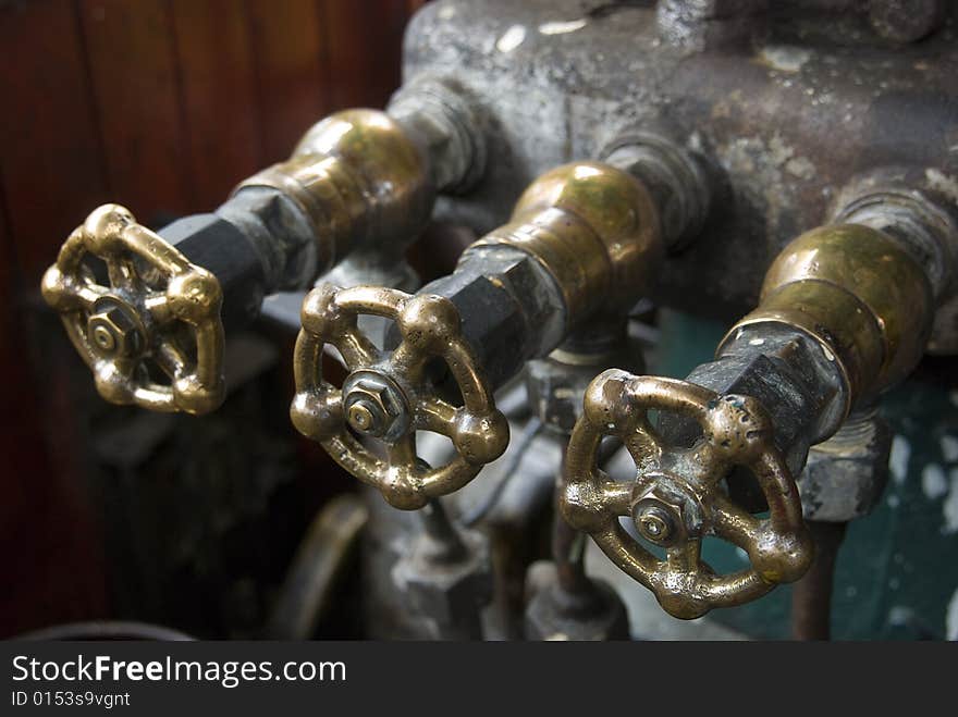 Three brass valves from the cockpit interior of an old steam engine. Shallow depth of field.