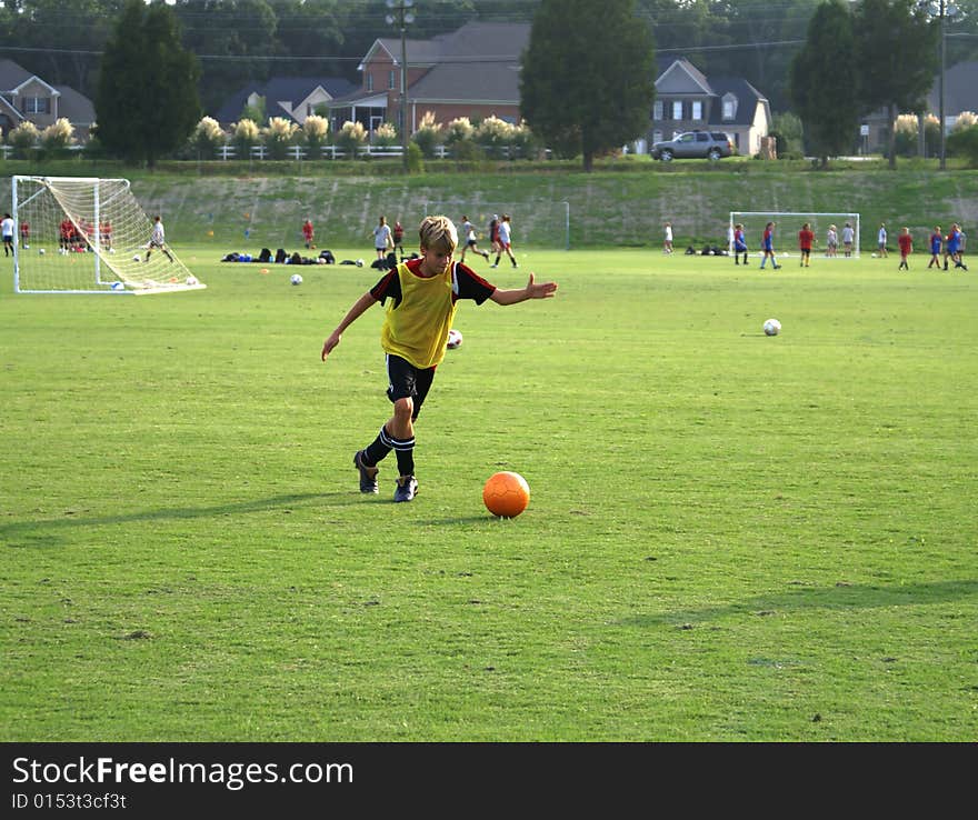 Boy kicking a ball on the field.