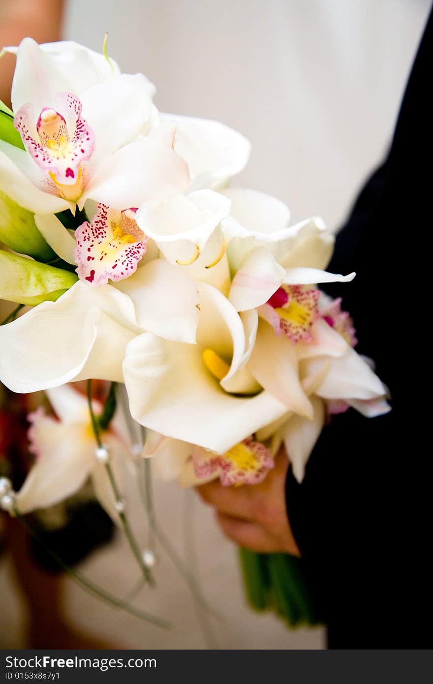 Groom holding a bouquet of orchids and lilies