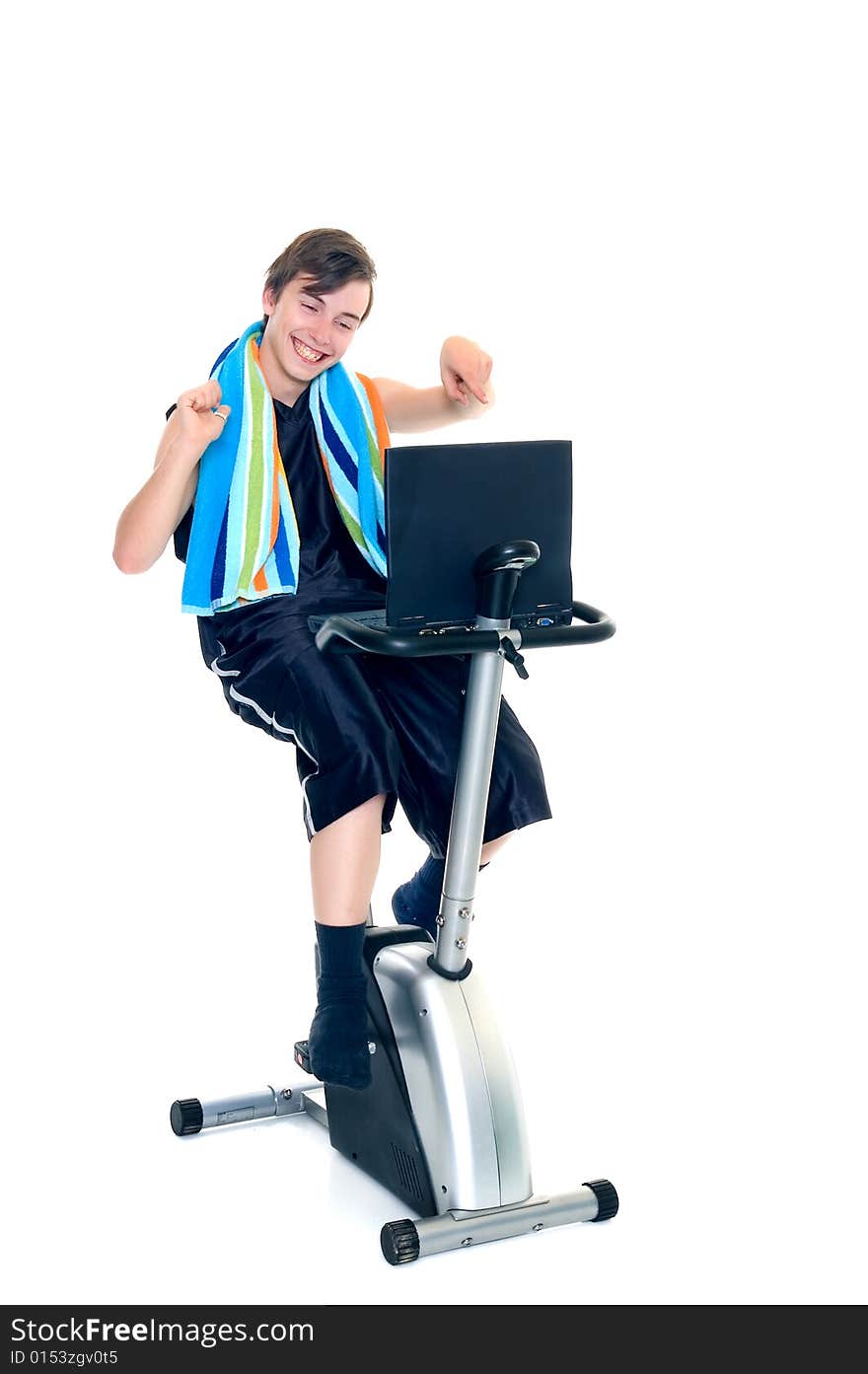 Young teenager boy doing fitness on home-trainer with laptop studying,. Young teenager boy doing fitness on home-trainer with laptop studying,