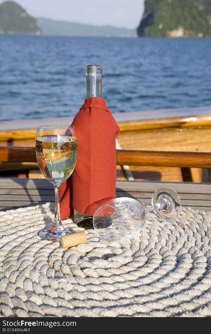 A bottle of wine and glasses on the deck of a yacht. A bottle of wine and glasses on the deck of a yacht