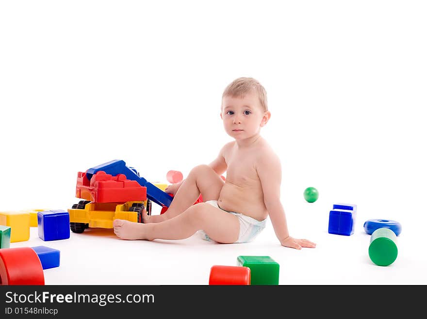 Little boy play with toys over white background with light shadows.