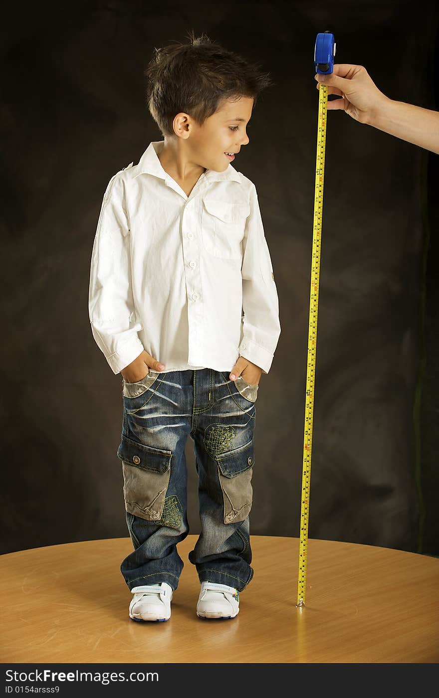 Boy is measured his increase by the tape-measure. Boy is measured his increase by the tape-measure