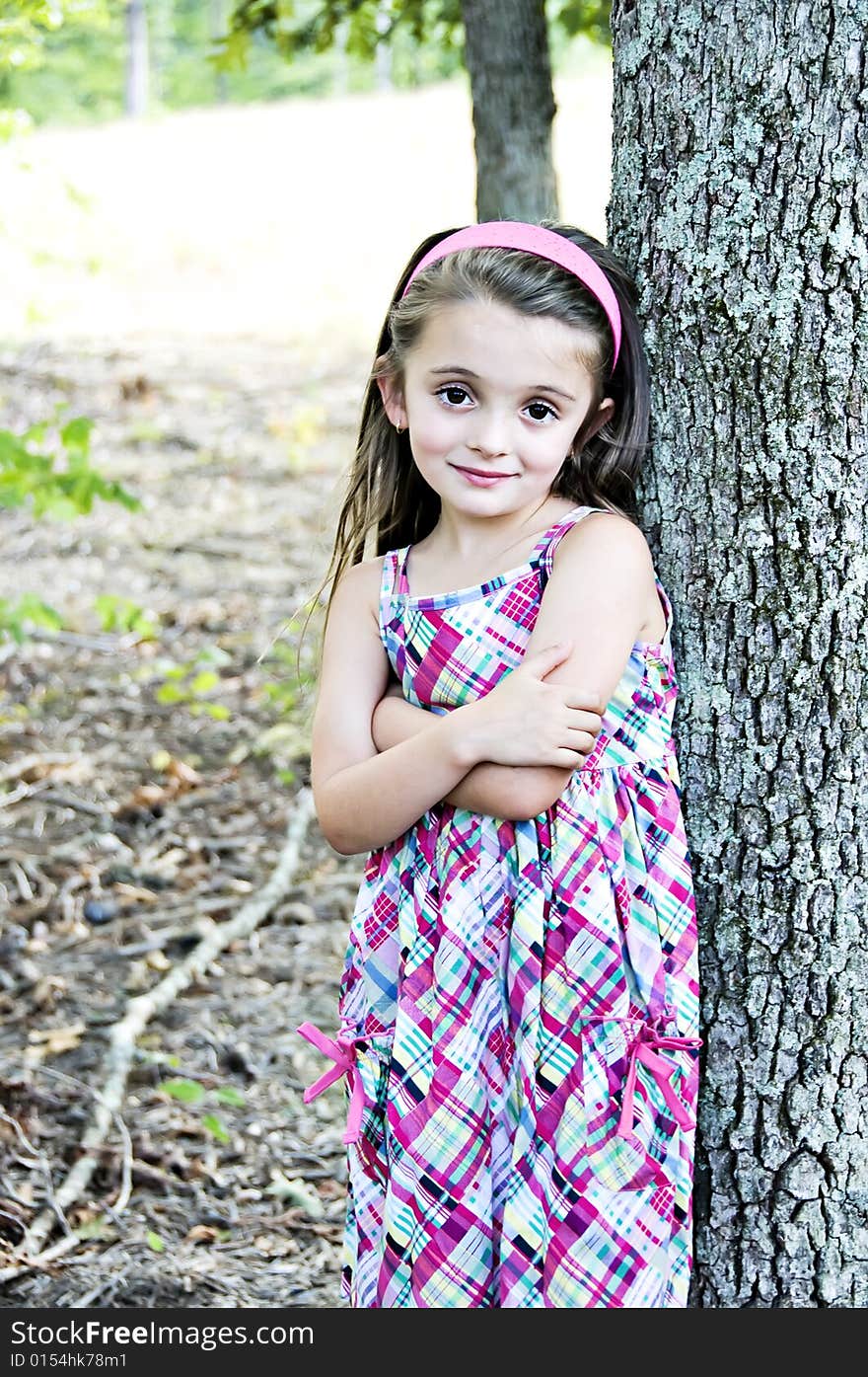 Young girl standing with arms folded next to a tree. Young girl standing with arms folded next to a tree.