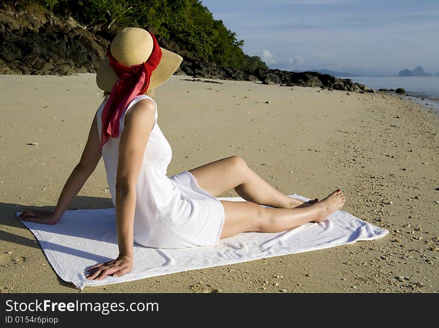 Woman with white dress and sun hat relaxing on the beach. Woman with white dress and sun hat relaxing on the beach