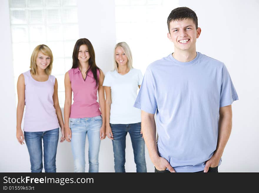 Four smiling friends standing and looking at camera. Focused on the boy who standing in front. Front view. Four smiling friends standing and looking at camera. Focused on the boy who standing in front. Front view.