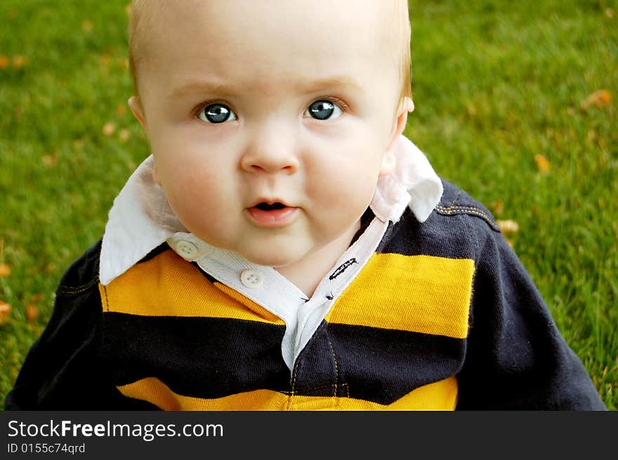 Cute baby boy looking thoughtful on the grass. Cute baby boy looking thoughtful on the grass