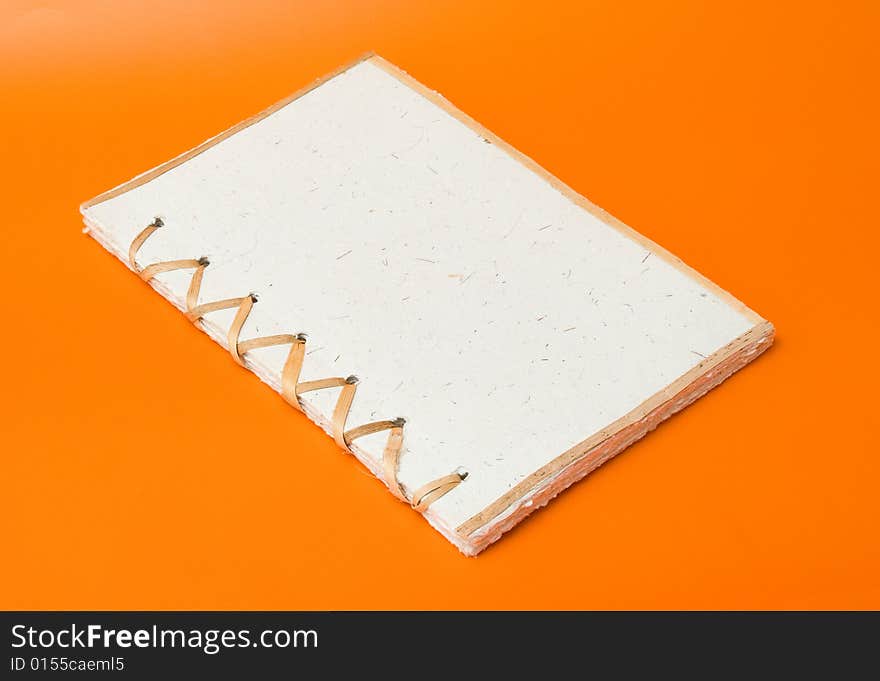 Recycled notepad over an orange background