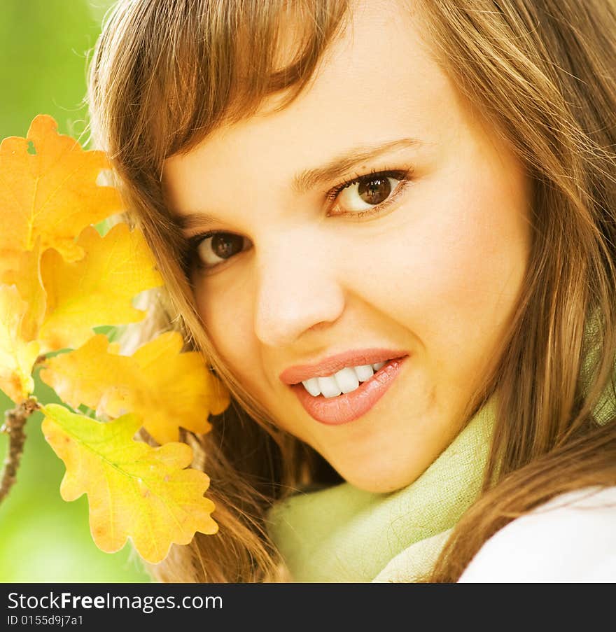 Beautiful romantic brunette with golden autumn leaf close-up portrait