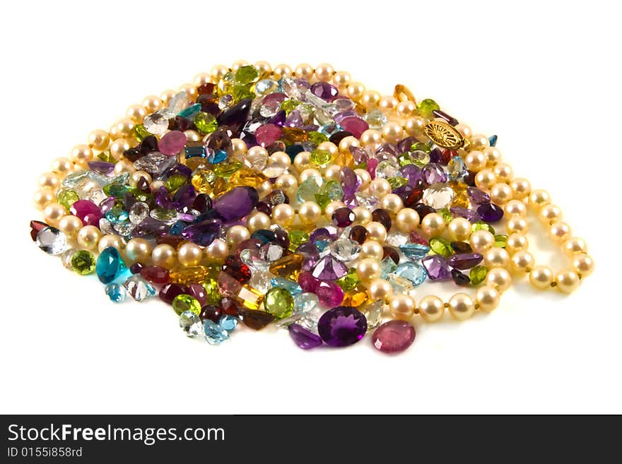 A large group of mixed faceted gemstones with pearls on a white background