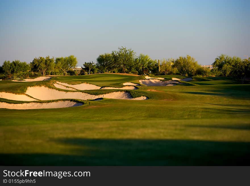 Golf course in the Arizona desert with mountains in the late afternoon sun