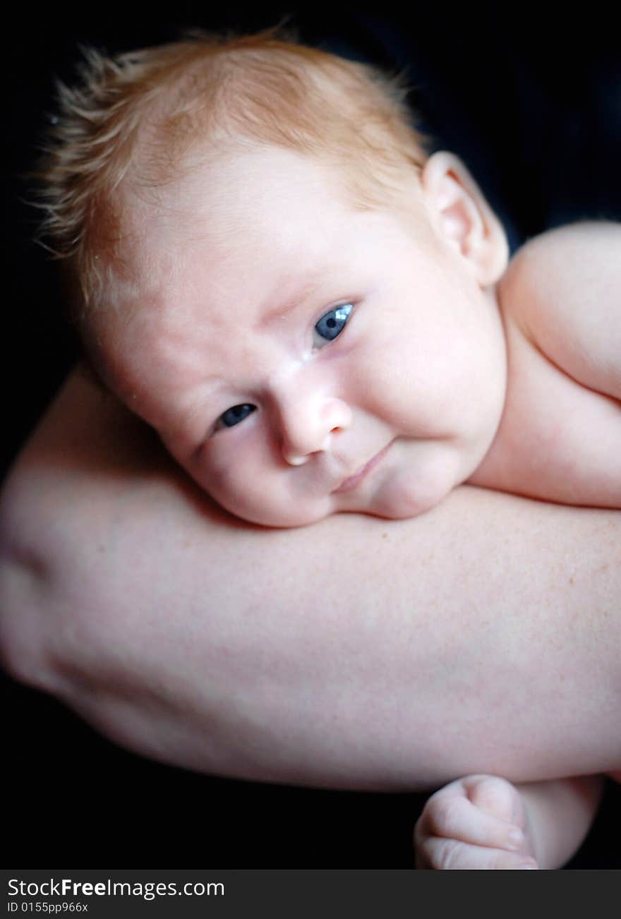 A baby is laying down in a studio on his mother's arm.  Vertically framed shot. A baby is laying down in a studio on his mother's arm.  Vertically framed shot.