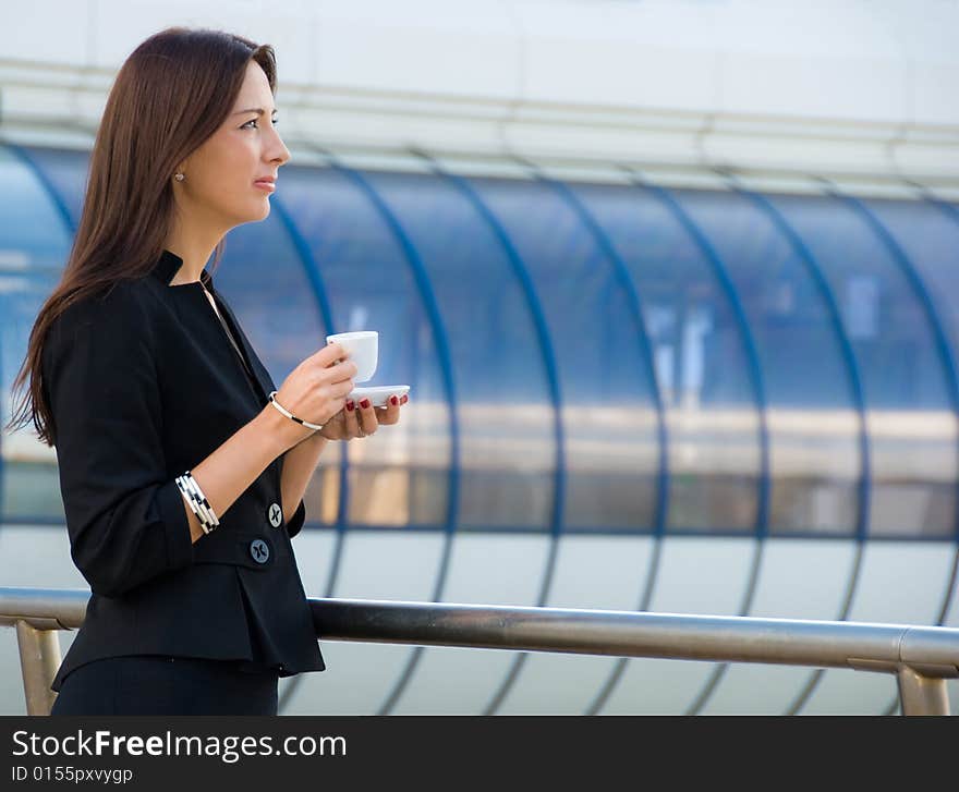 Business woman drinks a coffee outdoors in modern downtown. Business woman drinks a coffee outdoors in modern downtown