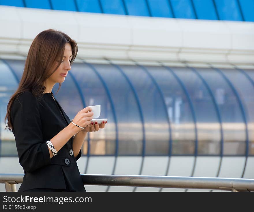 Business woman drinks a coffee outdoors in modern downtown. Business woman drinks a coffee outdoors in modern downtown