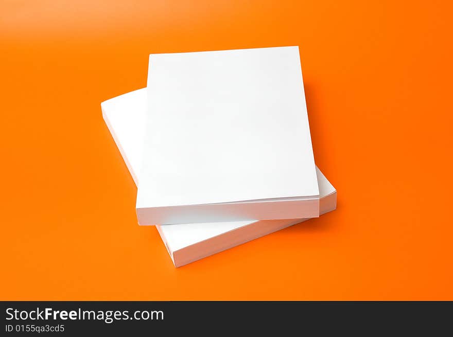 Two blank books over an orange background