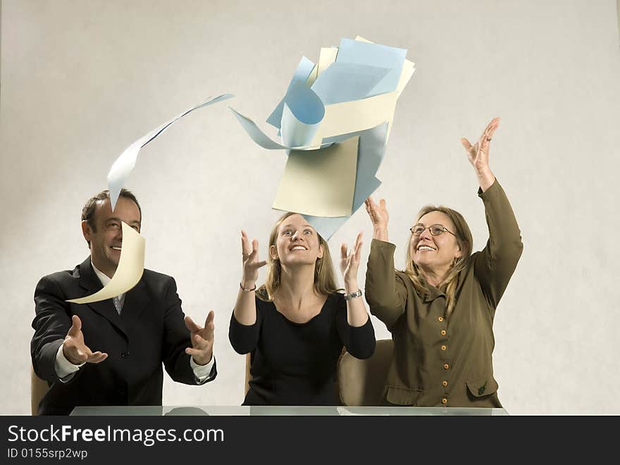 Three colleagues smiling and throwing their papers in the air. Horizontally framed photo. Three colleagues smiling and throwing their papers in the air. Horizontally framed photo.