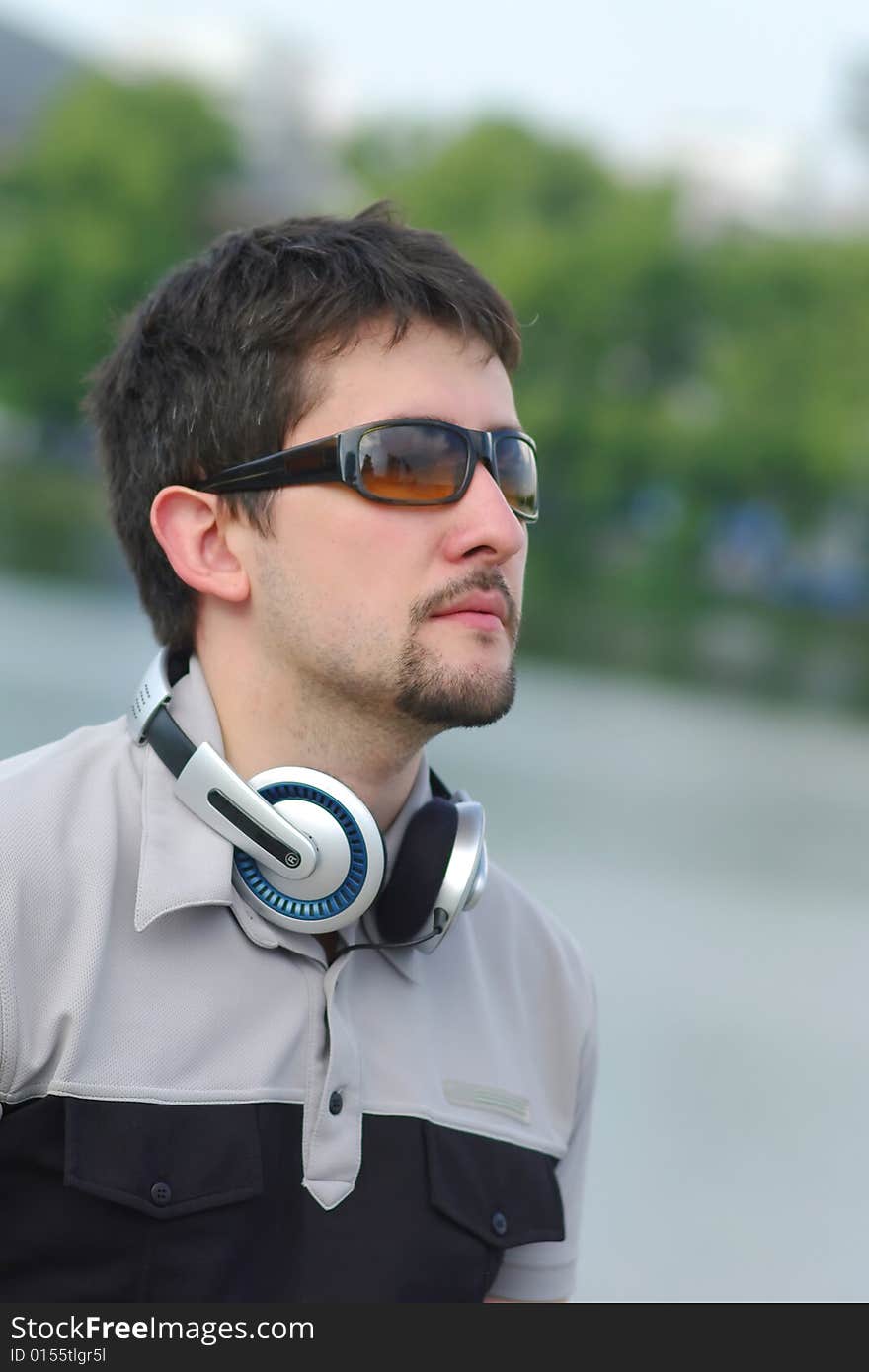 Young man with headphones on city view background looking at something