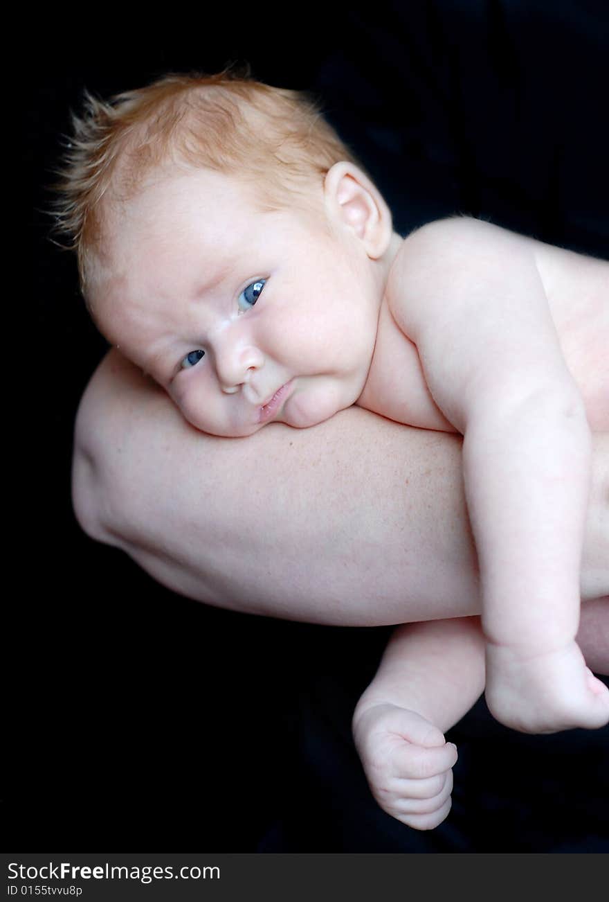 A baby is laying down in a studio on his mother's arm.  Vertically framed shot. A baby is laying down in a studio on his mother's arm.  Vertically framed shot.