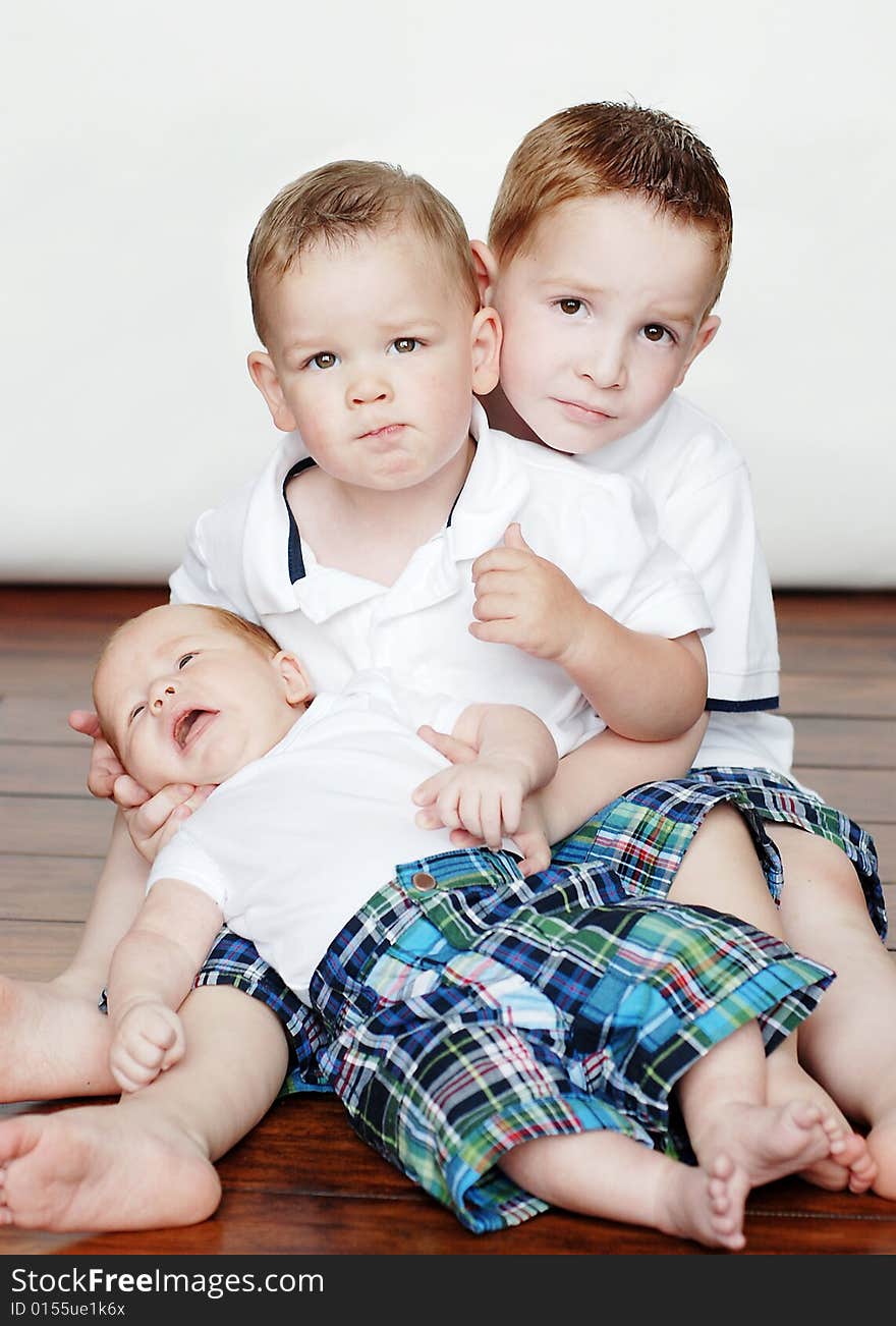 Photo of three young children posing on the floor for the camera. Vertically framed photo. Photo of three young children posing on the floor for the camera. Vertically framed photo.