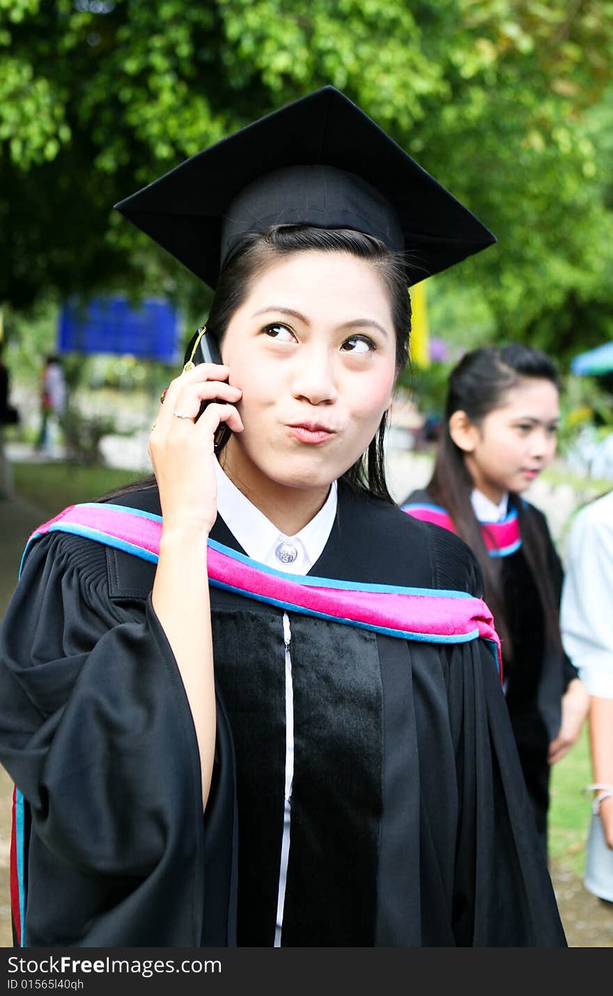 Asian university graduate talking on her cell phone.