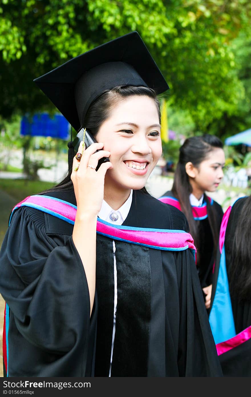 Asian university graduate talking on her cell phone.