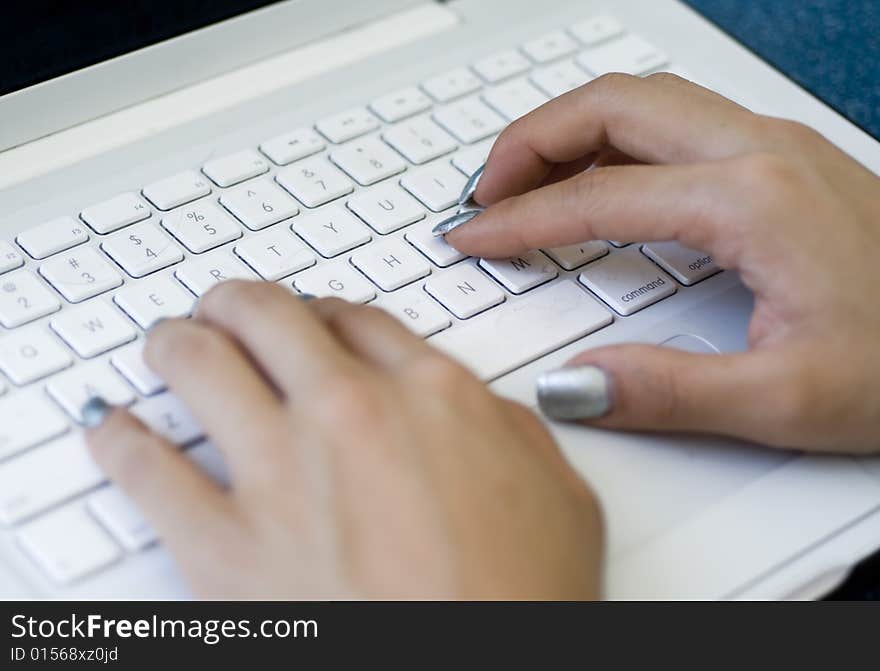 Hands typing on laptop keyboard and mouse pad