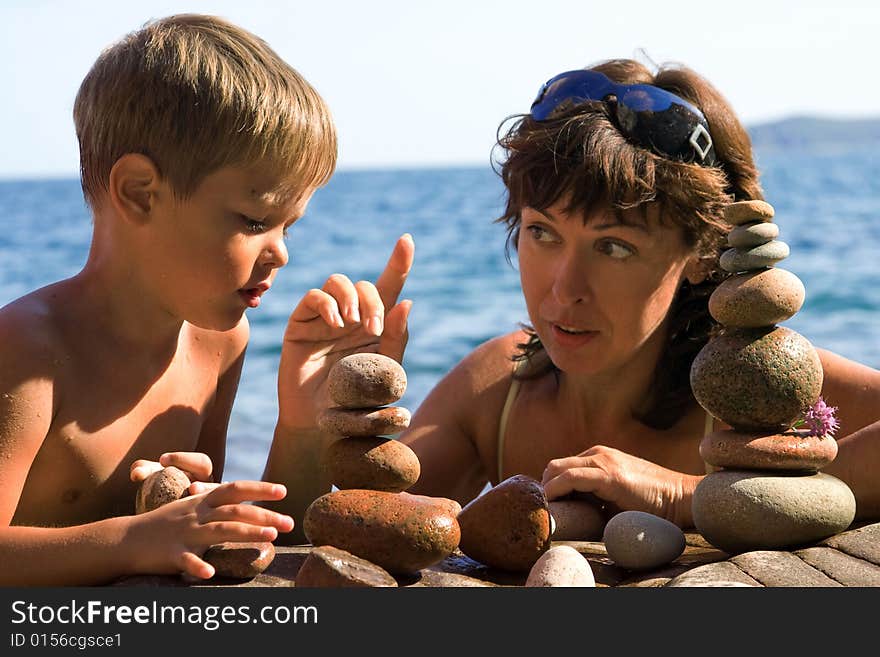 Mom with the son builds pyramids from the stones on the beach. Mom with the son builds pyramids from the stones on the beach