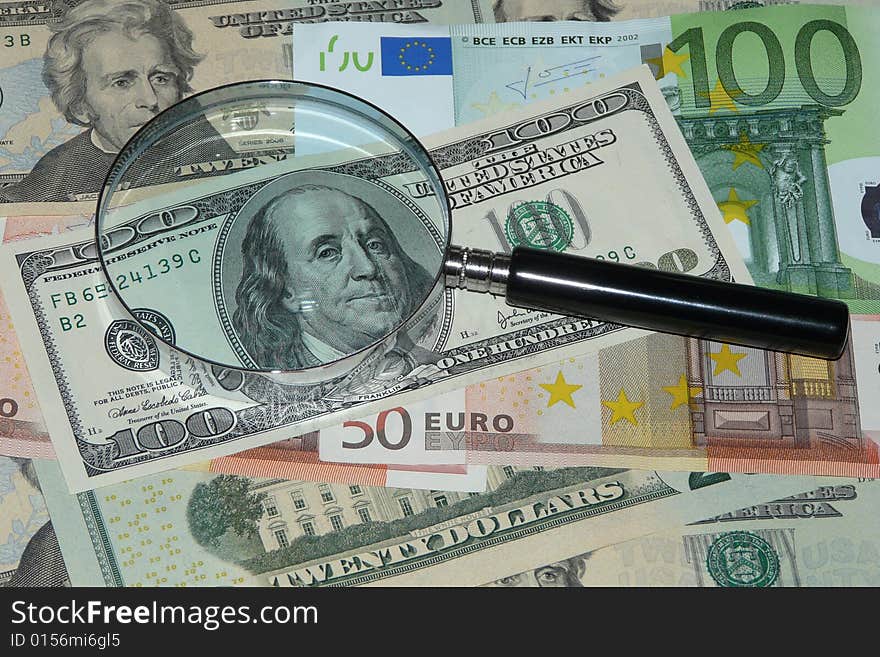 Notes of dollar and euro under magnifying glass