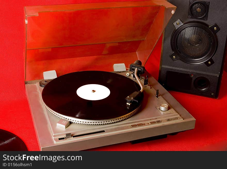 Record player with records and speaker on red ground