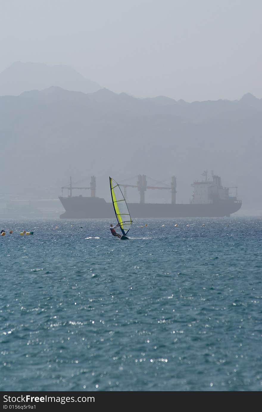 Windsurfing on the Red Sea in Eilat Israel. Cargo ship on background