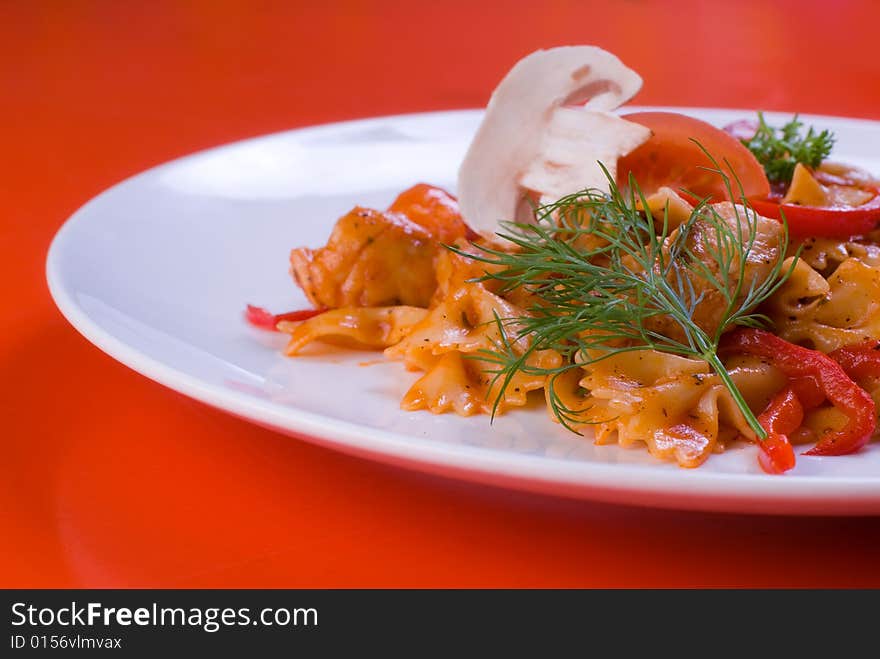 Freshly cooked plate of macaroni with chamignons and tomatoes sprinkled with fresh green herbs.